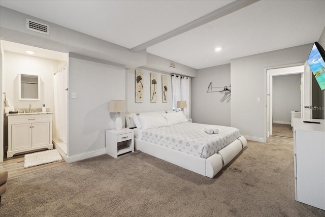 carpeted bedroom with ensuite bathroom and sink