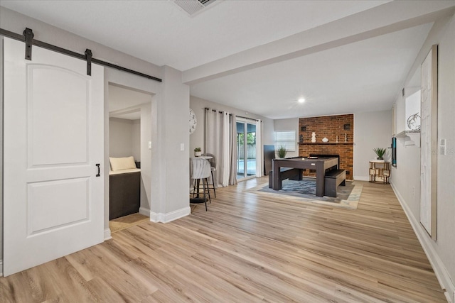 1504 E Mcberry St, Tampa, FL 33610 - living room featuring visible vents, a brick fireplace, light wood finished floors, baseboards, and a barn door