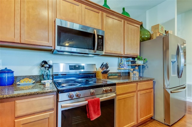 kitchen featuring dark stone countertops, light hardwood / wood-style flooring, and stainless steel appliances