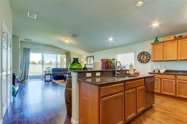 kitchen featuring sink, an island with sink, stainless steel dishwasher, and light hardwood / wood-style flooring