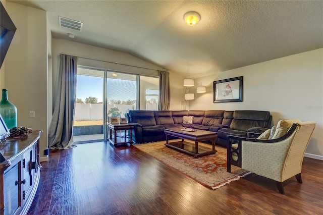 living room featuring dark hardwood / wood-style flooring, a textured ceiling, and vaulted ceiling