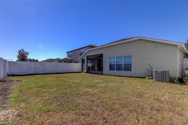 rear view of property with central AC and a lawn