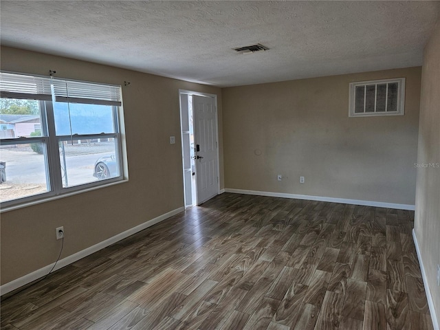 unfurnished room featuring a textured ceiling, dark hardwood / wood-style floors, and a wealth of natural light