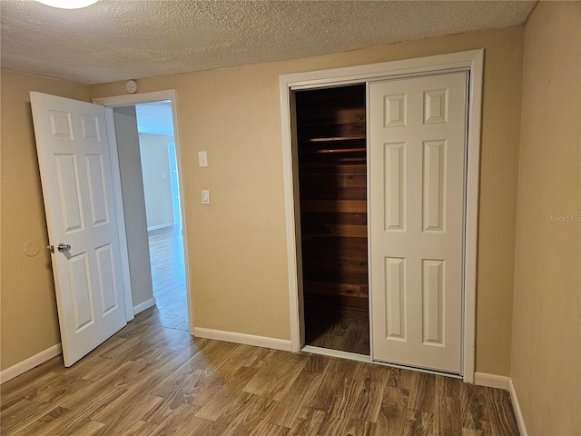 unfurnished bedroom featuring wood-type flooring, a textured ceiling, and a closet