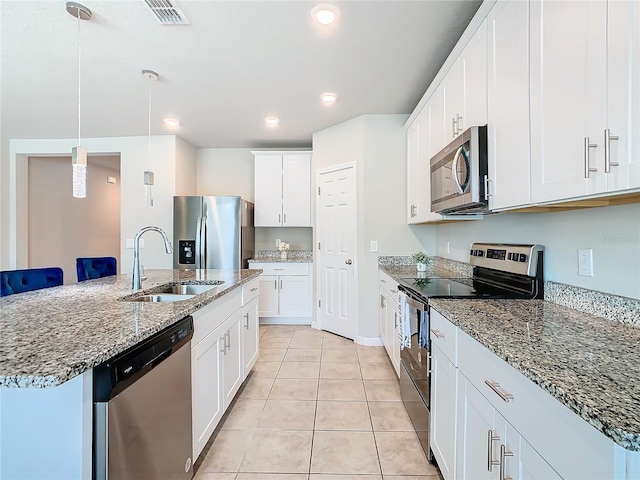 kitchen with sink, hanging light fixtures, an island with sink, white cabinetry, and stainless steel appliances