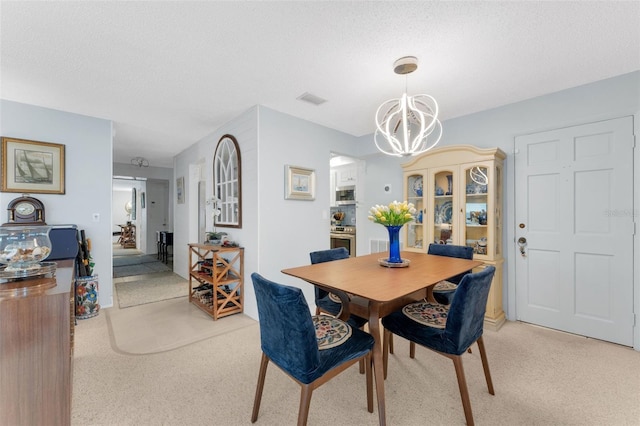 carpeted dining space with a notable chandelier and a textured ceiling