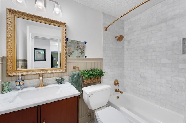 full bathroom with tiled shower / bath combo, toilet, a textured ceiling, and vanity