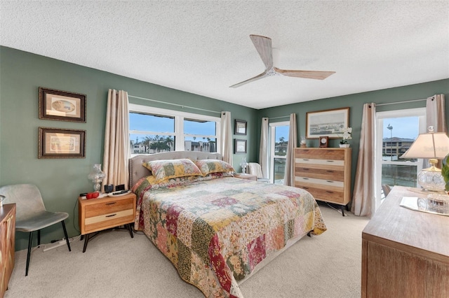 bedroom featuring ceiling fan, light colored carpet, and a textured ceiling