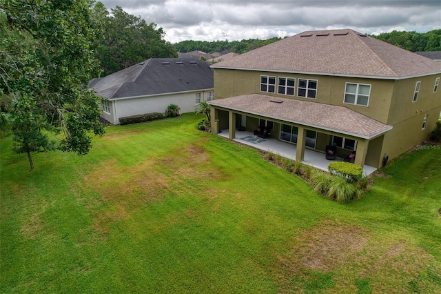 rear view of house featuring a lawn and a patio