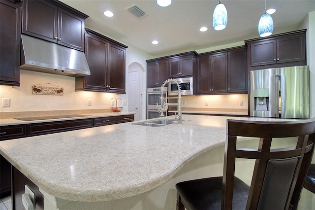 kitchen featuring a kitchen island with sink, a breakfast bar, decorative light fixtures, and appliances with stainless steel finishes