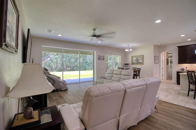 living room with a textured ceiling, light hardwood / wood-style flooring, and ceiling fan