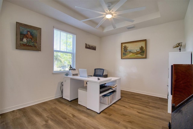 office featuring wood-type flooring, a tray ceiling, and ceiling fan