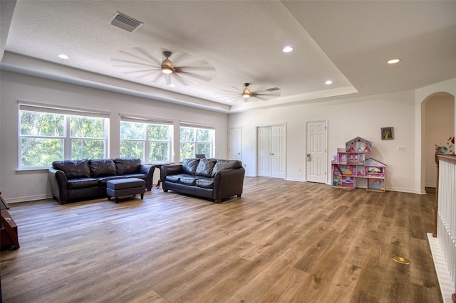 living room featuring hardwood / wood-style floors, a textured ceiling, a wealth of natural light, and a tray ceiling