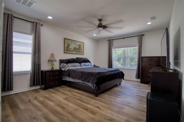 bedroom featuring ceiling fan, light hardwood / wood-style flooring, and a textured ceiling