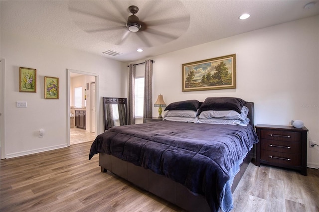 bedroom featuring a textured ceiling, ensuite bathroom, ceiling fan, and light hardwood / wood-style floors