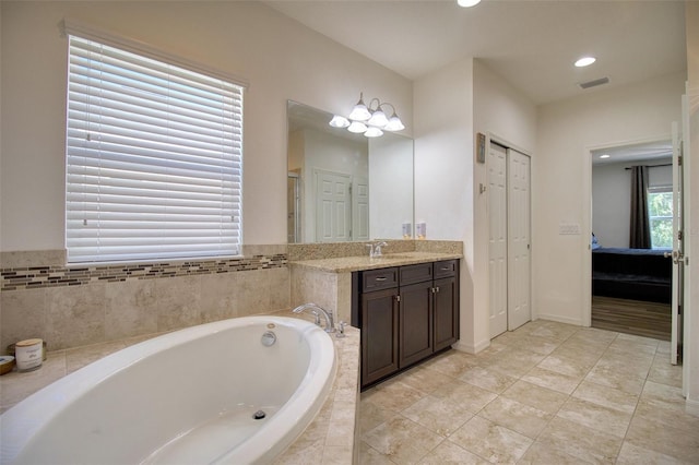 bathroom with vanity and tiled tub