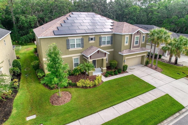 view of front facade with a front yard, solar panels, and a garage