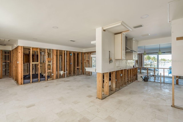 kitchen featuring wall chimney exhaust hood, kitchen peninsula, and backsplash