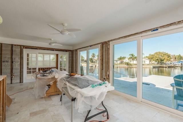 sunroom / solarium with ceiling fan and a water view