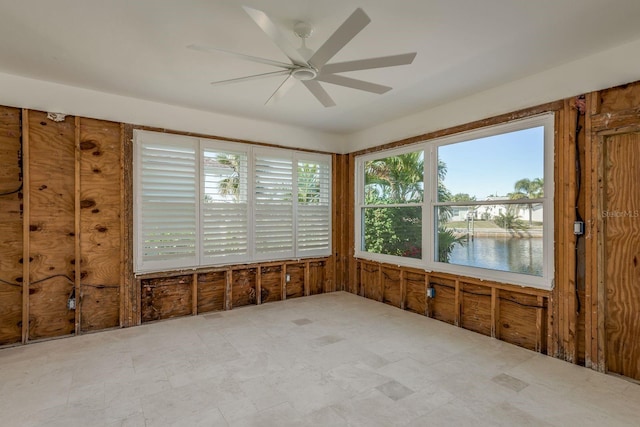 unfurnished sunroom featuring ceiling fan and a water view