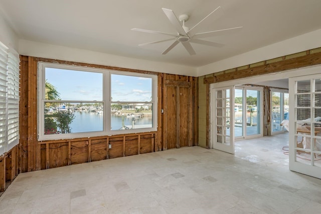 spare room with ceiling fan, french doors, and a water view