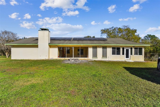 rear view of house featuring solar panels and a yard