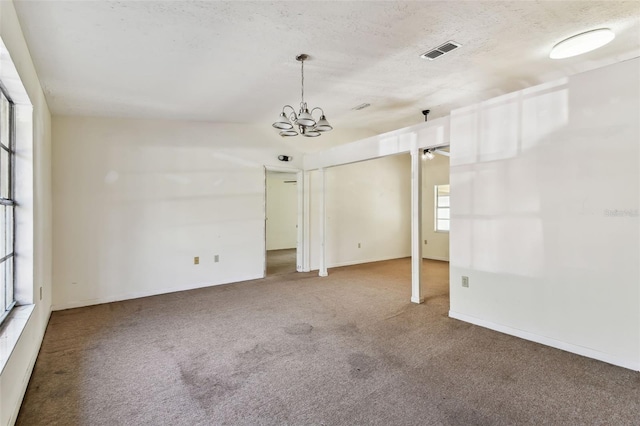 unfurnished room with carpet floors, a chandelier, and a textured ceiling