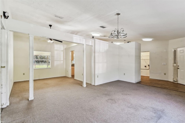 empty room with ceiling fan with notable chandelier and light colored carpet