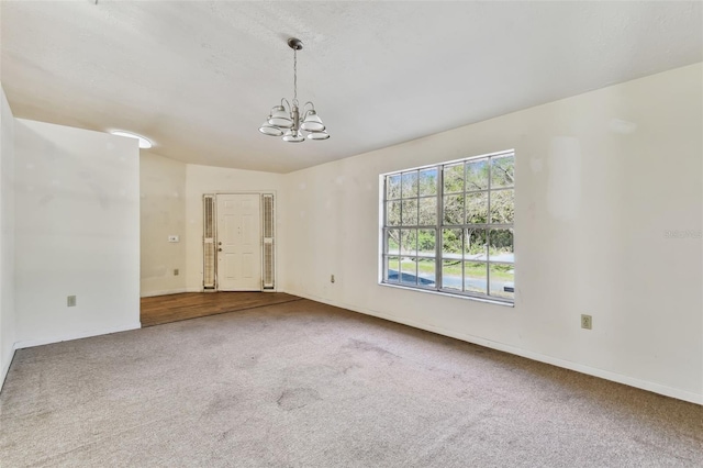 unfurnished room with carpet and a notable chandelier