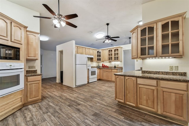 kitchen with vaulted ceiling, dark stone countertops, dark hardwood / wood-style floors, and white appliances