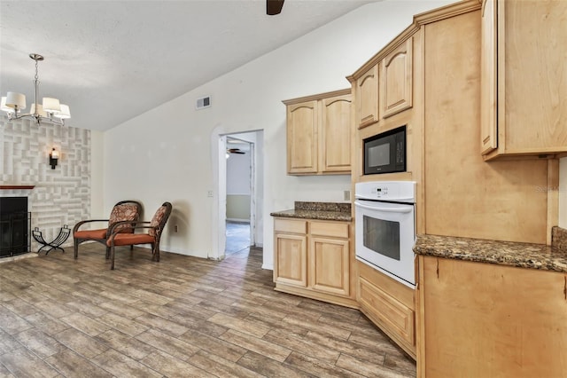 kitchen with light brown cabinets, white oven, decorative light fixtures, and black microwave