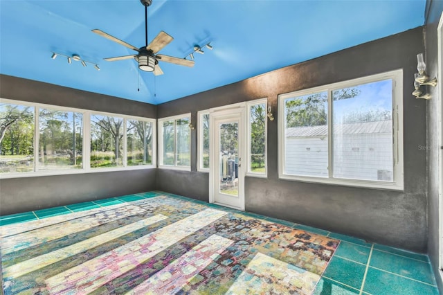 unfurnished sunroom featuring rail lighting and ceiling fan