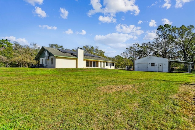 view of yard featuring a garage, a carport, and an outdoor structure