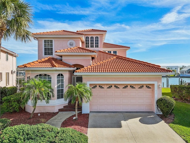 mediterranean / spanish-style house featuring a garage and a water view