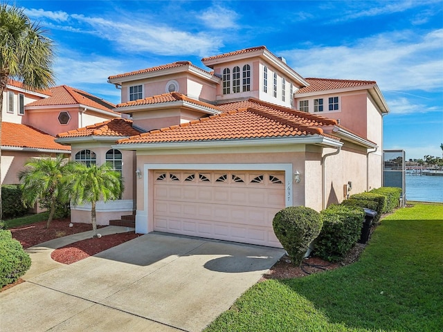 mediterranean / spanish house with a water view, a front lawn, and a garage