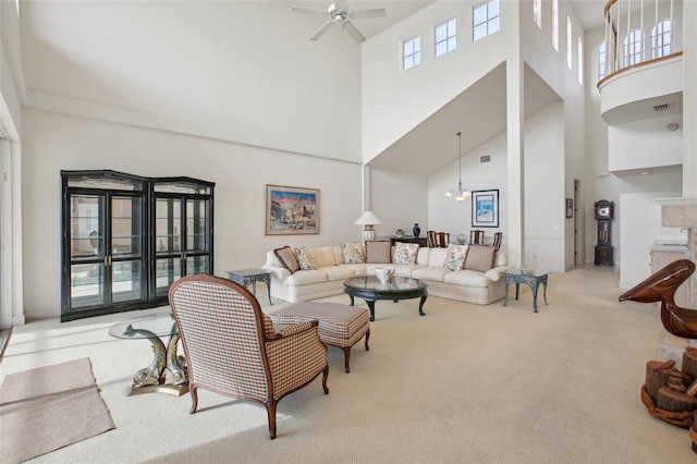 carpeted living room featuring ceiling fan with notable chandelier and a high ceiling