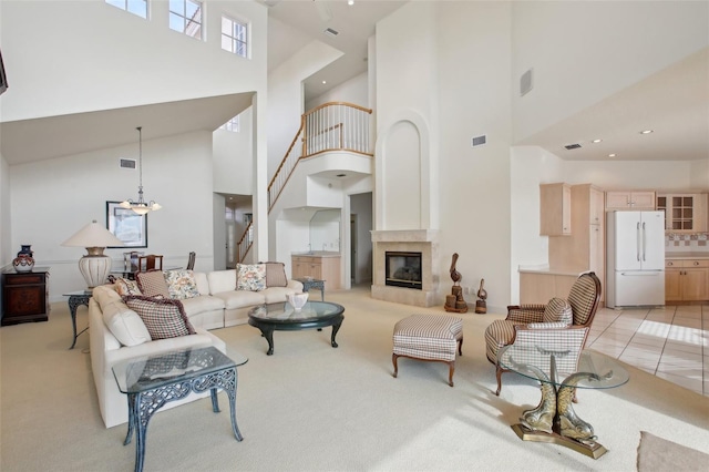 living room featuring light colored carpet, a towering ceiling, and a chandelier