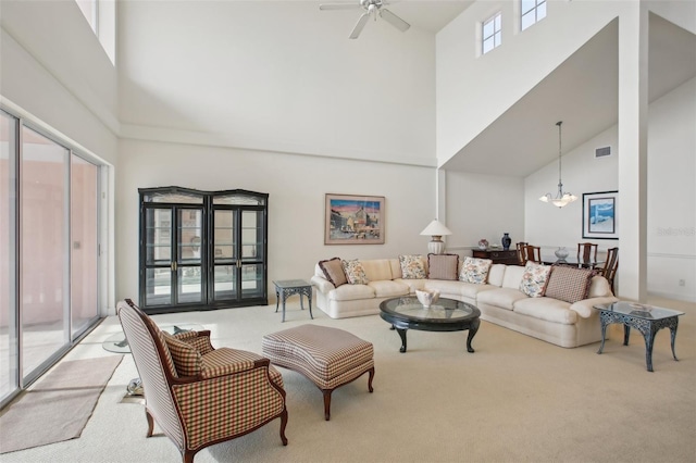 living room featuring ceiling fan with notable chandelier, a towering ceiling, and light carpet