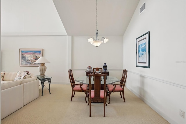 dining space featuring an inviting chandelier, light colored carpet, and vaulted ceiling