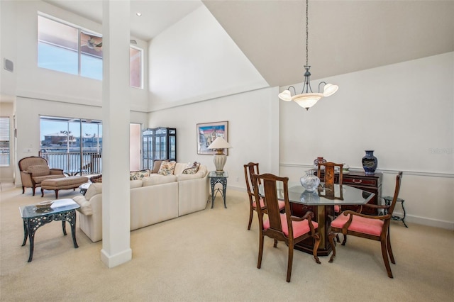 carpeted dining area featuring a water view and a towering ceiling