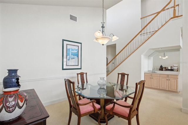 dining room with high vaulted ceiling, light colored carpet, and a notable chandelier