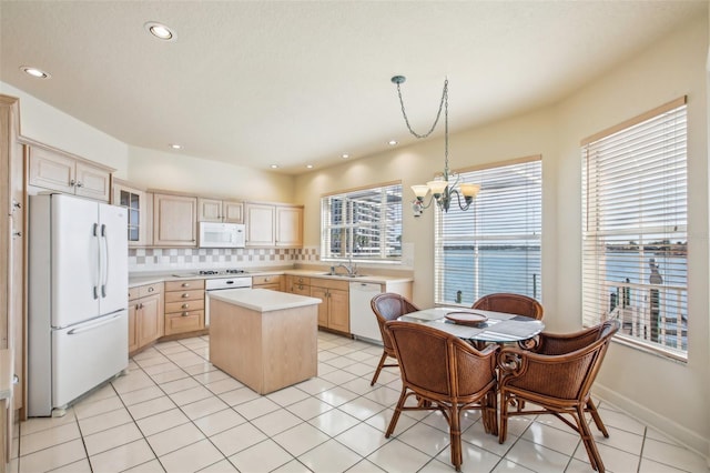 kitchen with light brown cabinets, white appliances, a kitchen island, and sink