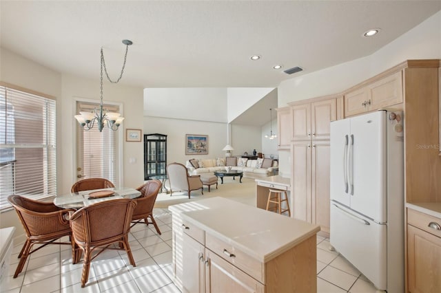 kitchen with white fridge, a chandelier, decorative light fixtures, light brown cabinetry, and light tile patterned floors