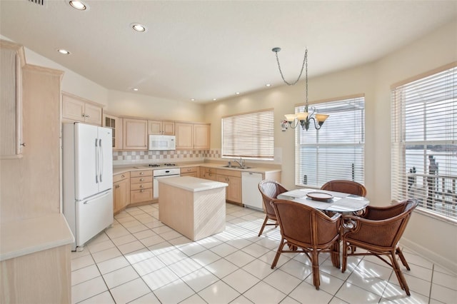 kitchen featuring decorative backsplash, white appliances, sink, light brown cabinets, and a center island