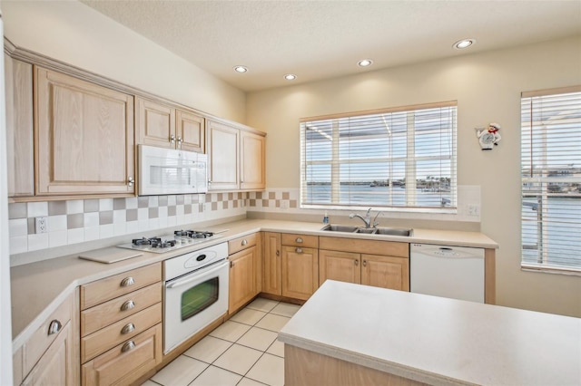 kitchen with light tile patterned flooring, light brown cabinetry, white appliances, and backsplash