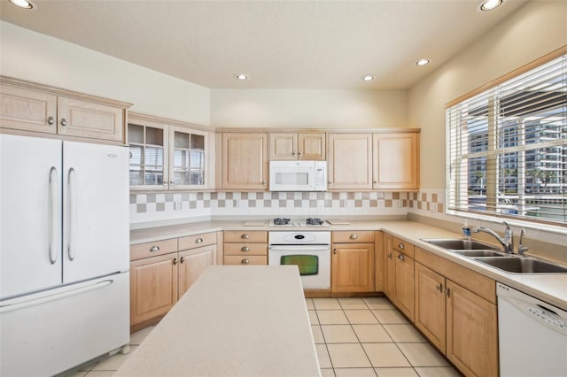 kitchen featuring light brown cabinetry, backsplash, white appliances, sink, and light tile patterned floors