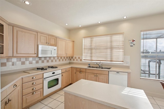 kitchen with light brown cabinetry, sink, light tile patterned floors, and white appliances