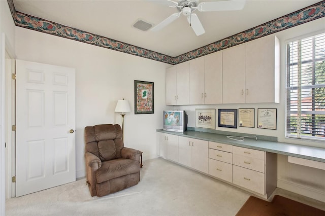 carpeted office space featuring ceiling fan and built in desk