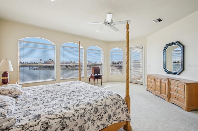 carpeted bedroom featuring ceiling fan and a water view