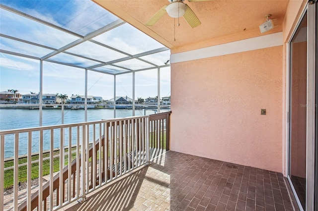 sunroom / solarium with ceiling fan and a water view